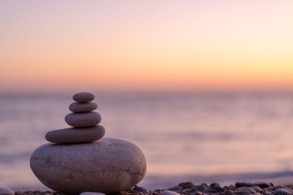 Perfect balance of stack of pebbles at seaside towards sunset. Concept of balance, harmony and meditation. Helping or supporting someone for growing or going higher up.